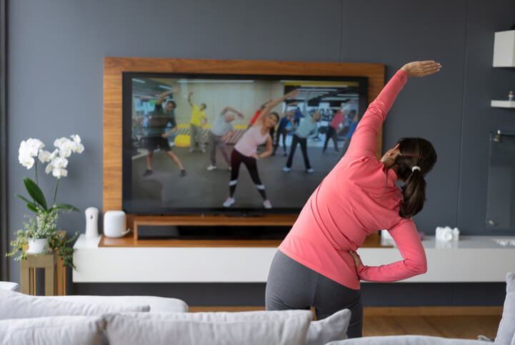 woman in workout clothes following stretching class on TV